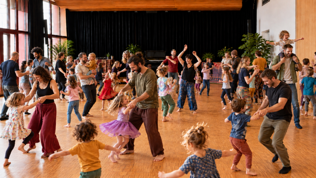 Kinder und Erwachsene tanzen gemeinsam im Saal, drehen sich und halten einander an den Händen.